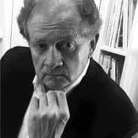 Portrait of a thoughtful older man with a serious expression, resting his chin on his hand, set against a backdrop of bookshelves filled with books.