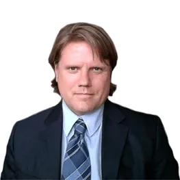 Professional man in a suit with a blue shirt and patterned tie, posing confidently against a white background. Ideal for business or corporate contexts.